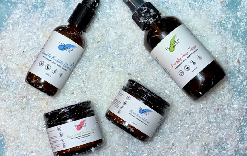 Four skincare products with labels on a textured surface
